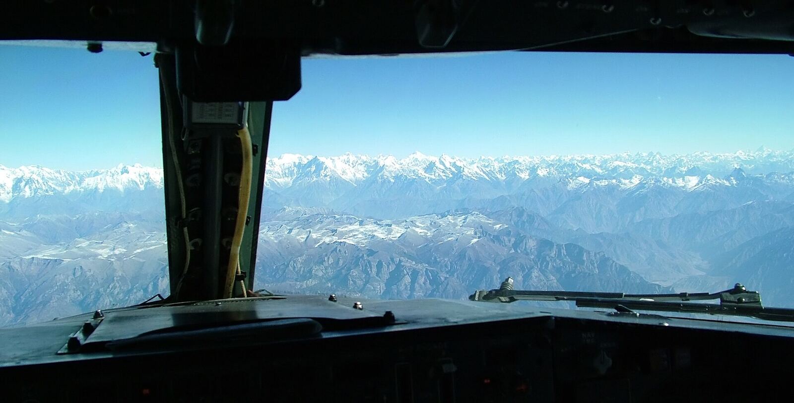 Snow-covered mountains seen through the windscreen of an airliner flight deck